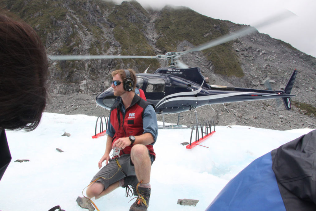 Fox-Glacier-heli-hike-guide-showing-how-to-attach-crampons-helicopter-behind