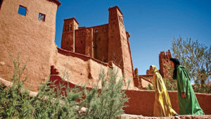 Morocco-Ouarzazate-women-walking-by village-walls